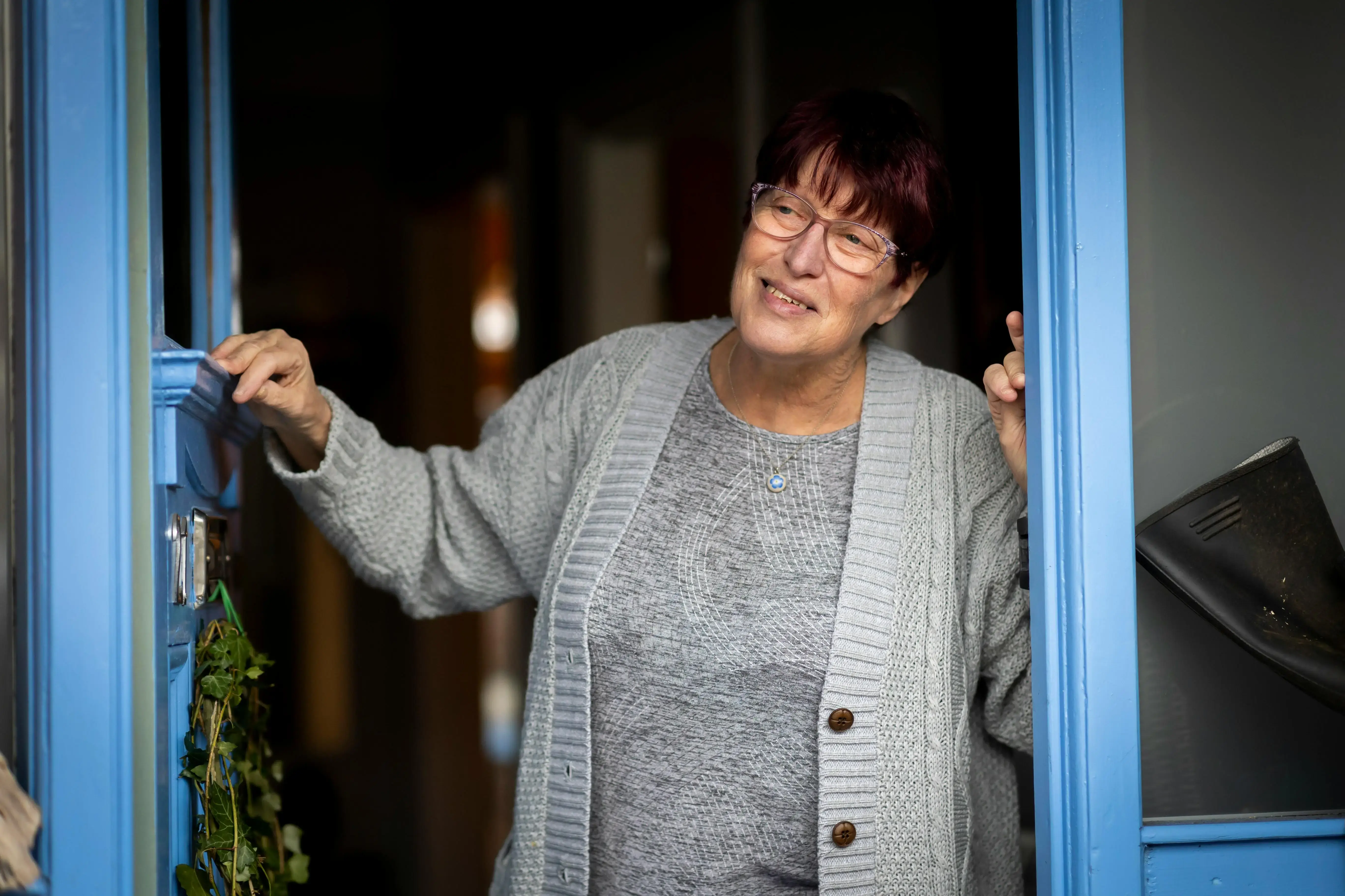 An older woman standing in the doorway of her home.